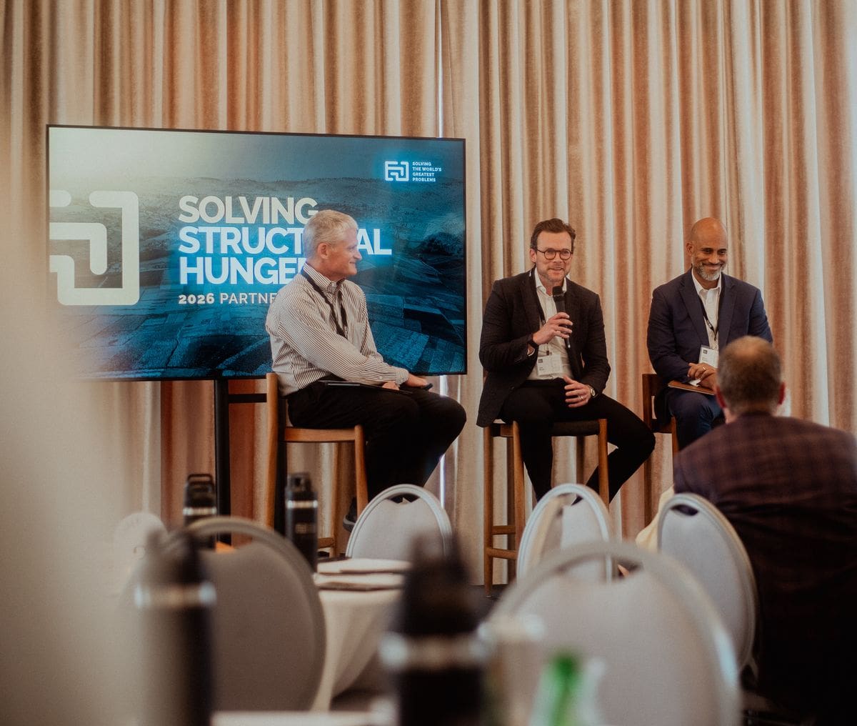 A panel on stage at a Faith Driven Entrepreneur conference, guests gathered in front of the screen