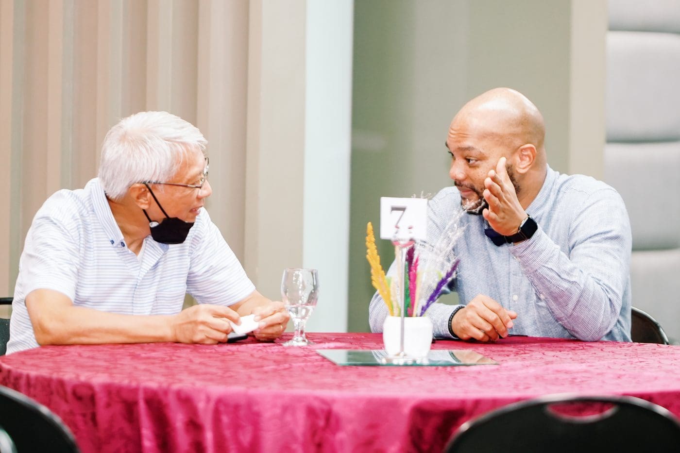 Two men talking across a table at an FDE gathering